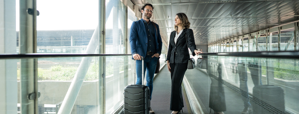 Congress support-Kongressbegleitung: Zwei Personen, die sich auf einem Rollband am Flughafen unterhalten.